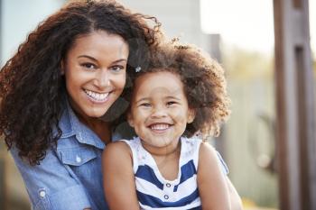 Mixed race mother and young daughter smile to camera outside