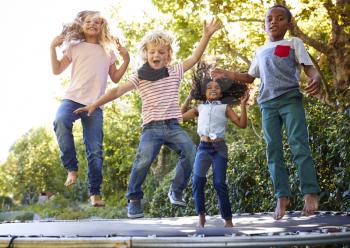 Four kids having fun together on a trampoline in the garden
