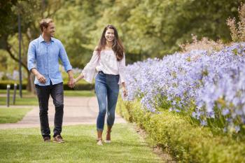 Couple Holding Hands On Romantic Walk In Park Together