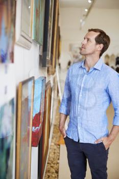 Man Looking At Paintings In Art Gallery