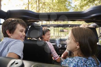 Family Driving In Open Top Car On Countryside Road Trip