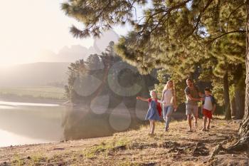 Children Walk By Lake With Parents On Family Hiking Adventure