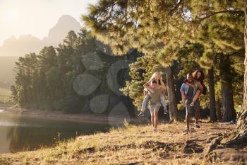 Group Of Young Friends Enjoying Walk By Lake On Hiking Adventure