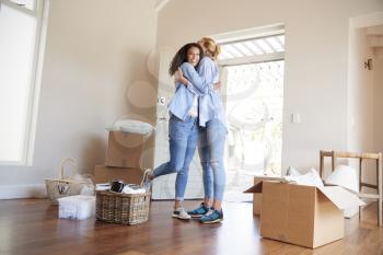 Female Friends Hugging In Lounge Of New Home On Moving Day