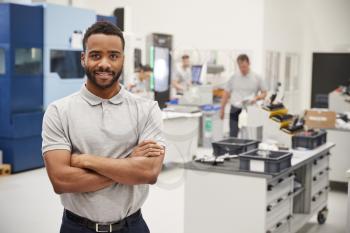 Portrait Of Male Engineer On Factory Floor Of Busy Workshop
