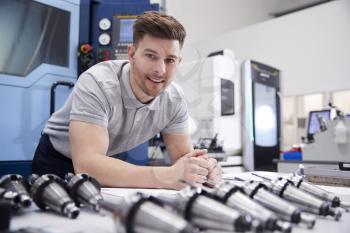 Portrait Of Male Engineer With CAD Drawings In Factory