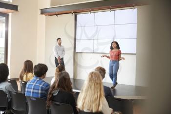 Female Student Giving Presentation To High School Class In Front Of Screen