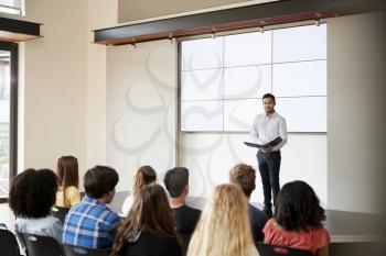 Teacher Giving Presentation To High School Class In Front Of Screen