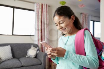 Young Girl With Backpack In Bedroom Ready To Go To School Checking Mobile Phone