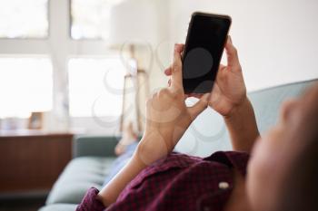 Close Up Of Woman Lying On Sofa At Home Using Mobile Phone