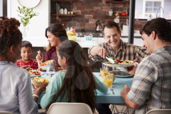 Multi Generation Family Enjoying Meal Around Table At Home Together