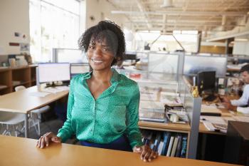 Black female architect in open plan office smiling to camera