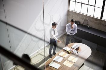 Two businessmen talk standing in an office, elevated view
