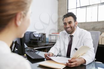 Hispanic male doctor in consultation with female patient
