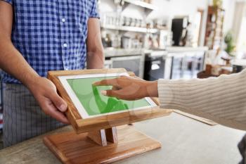 Customer using touch screen sales terminal at cafe, close up