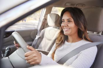 Young woman in car driving seat looking ahead, close up