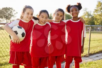 Four young girls in football strip looking to camera smiling