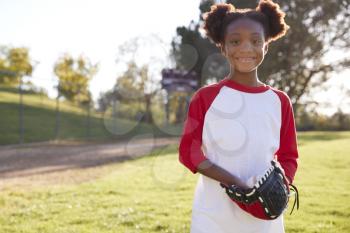 Young Black girl holding baseball mitt smiling to camera