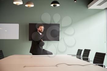 Portrait Of Young Businessman Sitting On Boardroom Table At Graduate Recruitment Assessment Day In Office
