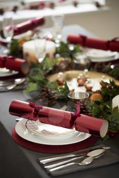 Close up of decorated Christmas table setting, with centrepiece and Christmas crackers arranged on plates