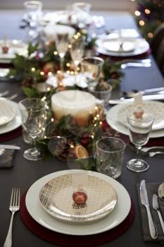 Christmas table setting with bauble name card holder arranged on a plate and green and red decorations, elevated view