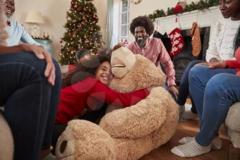 Children Playing With Giant Teddy Bear As Multi-Generation Family Open Gifts On Christmas Day