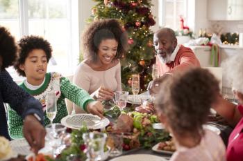 Young black woman eating Christmas dinner with her mixed race multi generation family, close up