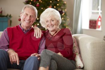 Portrait Of Senior Couple Sitting On Sofa In Lounge At Home On Christmas Day