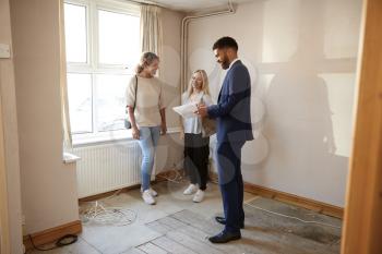 Two Female Friends Buying House For First Time Looking At House Survey With Realtor