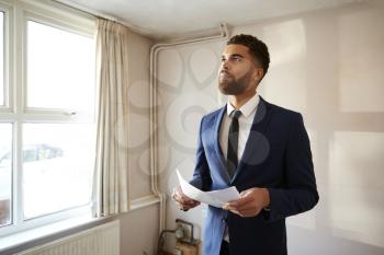 Male Realtor Looking At House Details In Property For Renovation