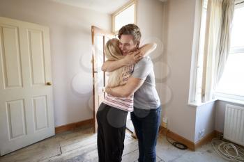 Excited Young Couple Hugging By Front Door Of New Home