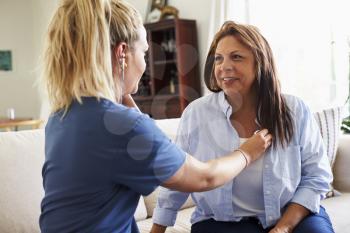 Female healthcare worker giving a middle aged woman a check up during a home health visit