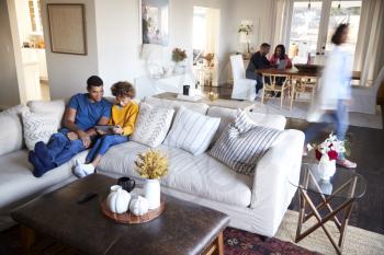 Three generation family family spending time in their open plan living room and kitchen diner, father and daughter in the foreground, elevated view, motion blur