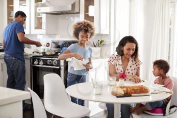 Young mixed race family preparing a meal together in their kitchen