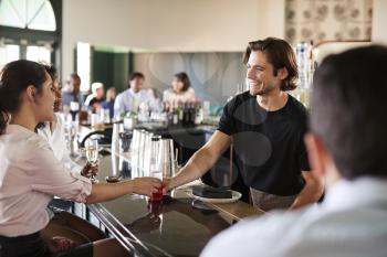 Bartender Serving Two Businesswomen Meeting For After Works Drinks