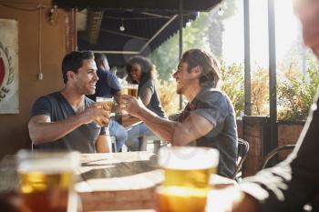 Two Male Friends Meeting In Sports Bar Making Toast Together