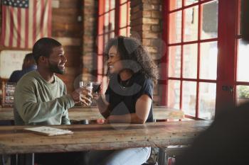 Young Couple Meeting In Sports Bar Making Toast Together