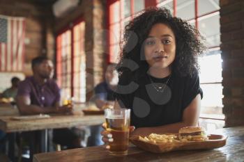 Portrait Of Woman In Sports Bar Eating Burger And Fries