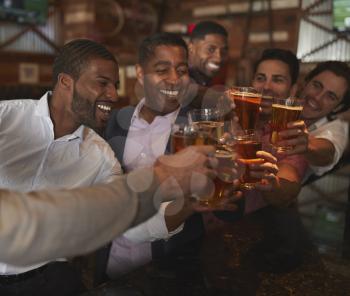 Group Of Male Friends On Night Out For Bachelor Party In Bar Making Toast Together