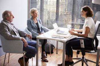 Smiling Senior Couple Meeting With Female Financial Advisor In Office