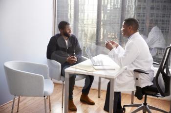 Man Having Consultation With Male Doctor In Hospital Office