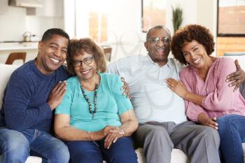 Middle aged black couple and parents sitting at home, smiling to camera