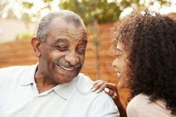 Senior black man and his adult granddaughter laughing outdoors, close up