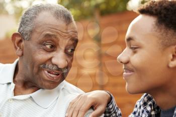 Senior black man talking with his young adult grandson, close up