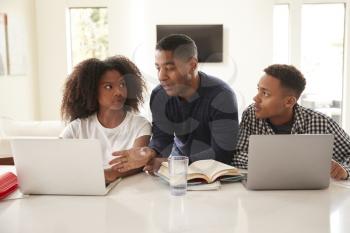 Middle aged black dad helping his teen kids with their homework, front view, close up