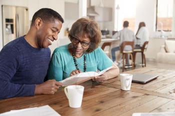 Middle aged black man looking through a photo album with his mother at home, close up