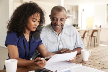 Female healthcare worker checking test results with a senior man during a home health visit