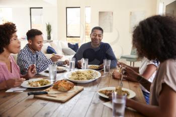 Middle aged black man sitting at the table eating dinner with his wife and family, close up