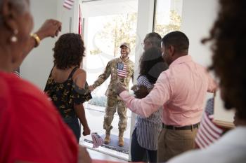 Young black soldier returning home to a surprise family party, selective focus, over shoulder view