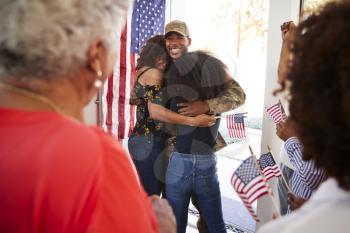 Millennial black soldier embracing his family after returning home,close up, over shoulder view